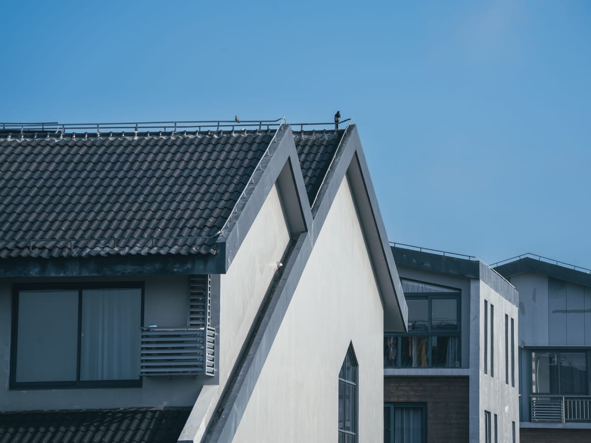 Modern residential buildings with unique architectural rooftops under a clear blue sky.