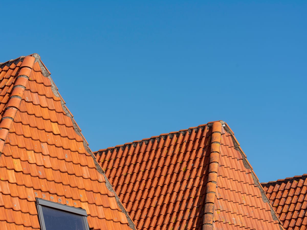 Close-up of red tiled roofs under a clear blue sky, showcasing architectural design.