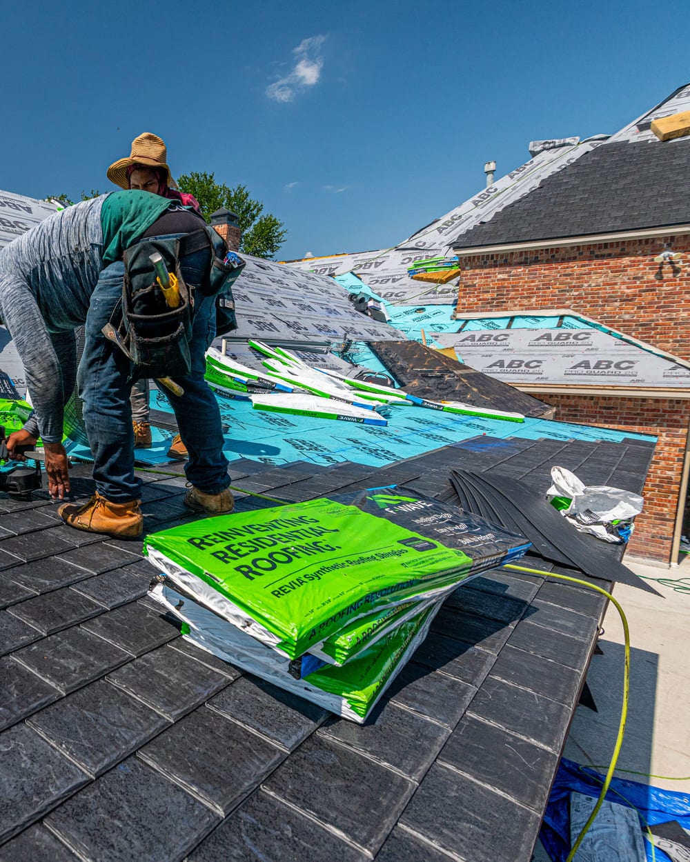 Workers installing a synthetic slate roof on a brick house in Fort Worth, Texas.